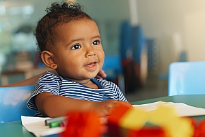 an infant playing with toy blocks at a daycare