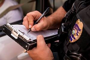 Police officer filling out ticket covered with police liability insurance