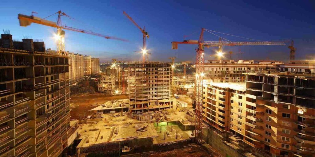 lots of tower cranes build large residential buildings at night