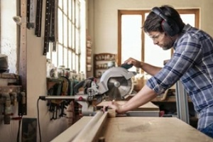 woodworker using wood cutting saw with woodworking insurance