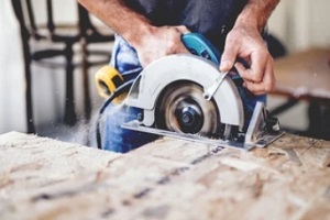 worker cutting plyboard with insurance for woodworking business