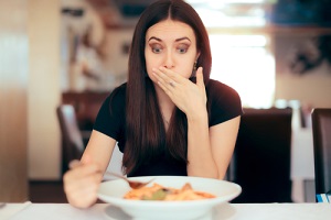 woman feeling sick while eating bad food in a restaurant