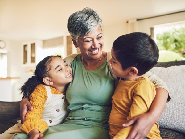 Hug, grandmother or happy kids on a sofa with love enjoying quality bonding time together in family home. Smile, affection or funny senior grandparent with children siblings on house couch laughing.