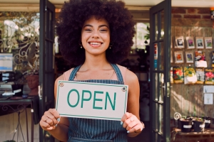 Open sign, black woman and garden shop owner of a small business manager portrait happy. Smile of a retail store entrepreneur with welcome shopping board and business owner with plant products.