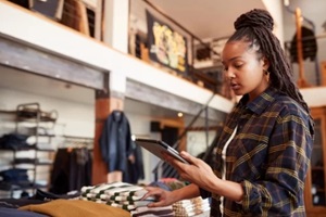 female worker of fashion store using digital tablet to check stock in clothing store