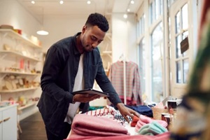 male small business owner checks stock in shop using digital tablet